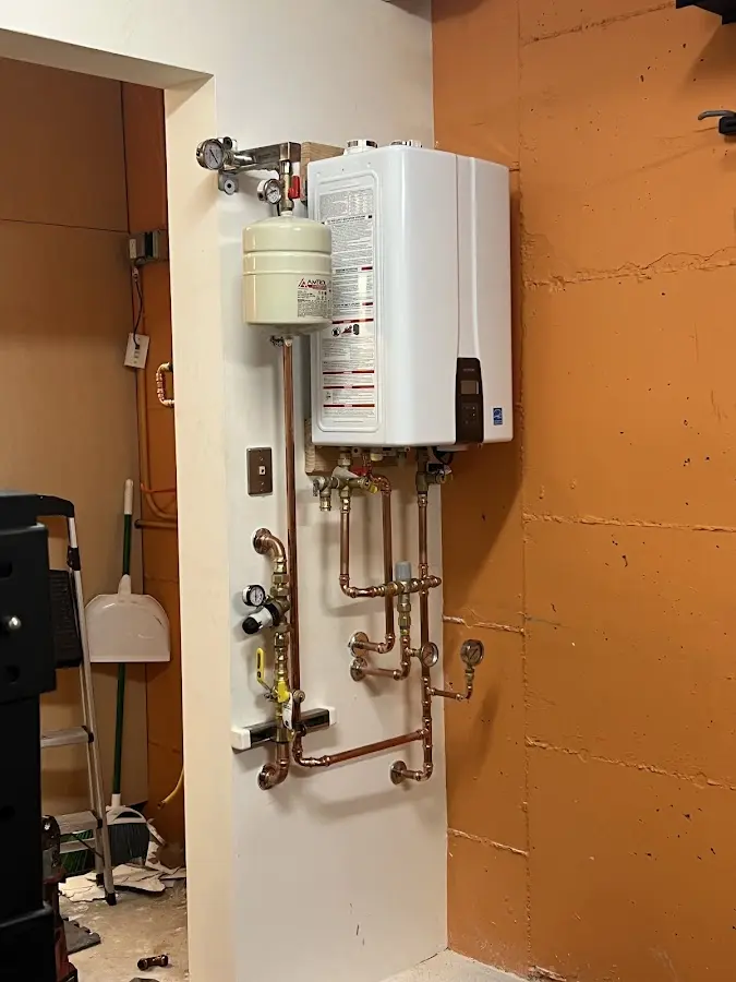 Plumbing technician inspecting water heater connections in Monticello